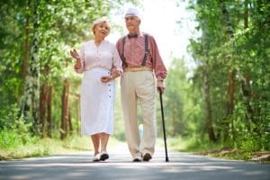 Elderly man and woman walking with cane in park