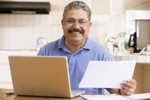 Senior man with laptop and letter in kitchen 1