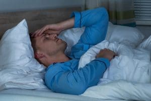 Man holding his head in bed in pain