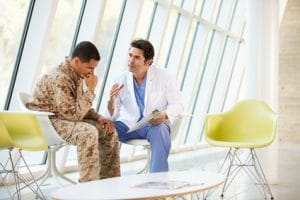A doctor sitting with a veteran going over paperwork