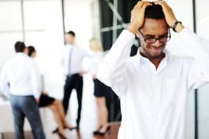 Man with his hands on his head with people in background