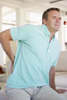 Middle aged man holding lower back in pain